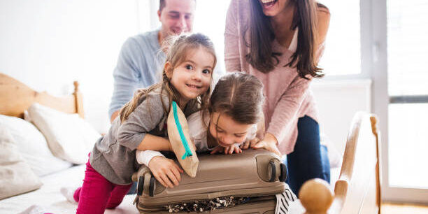 Portrait of a young happy family with two children packing for holiday at home.